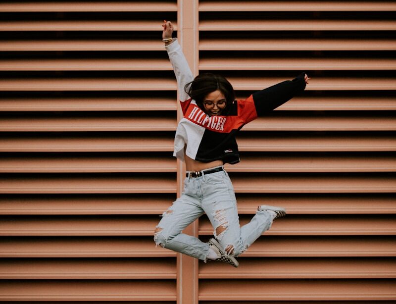 woman jumping in front of brown wall