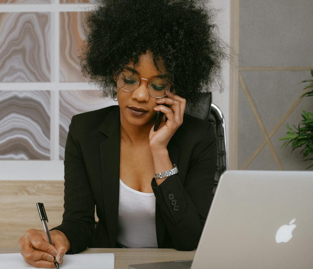 Businesswoman making a phone call while working at the desk, focused and professional.